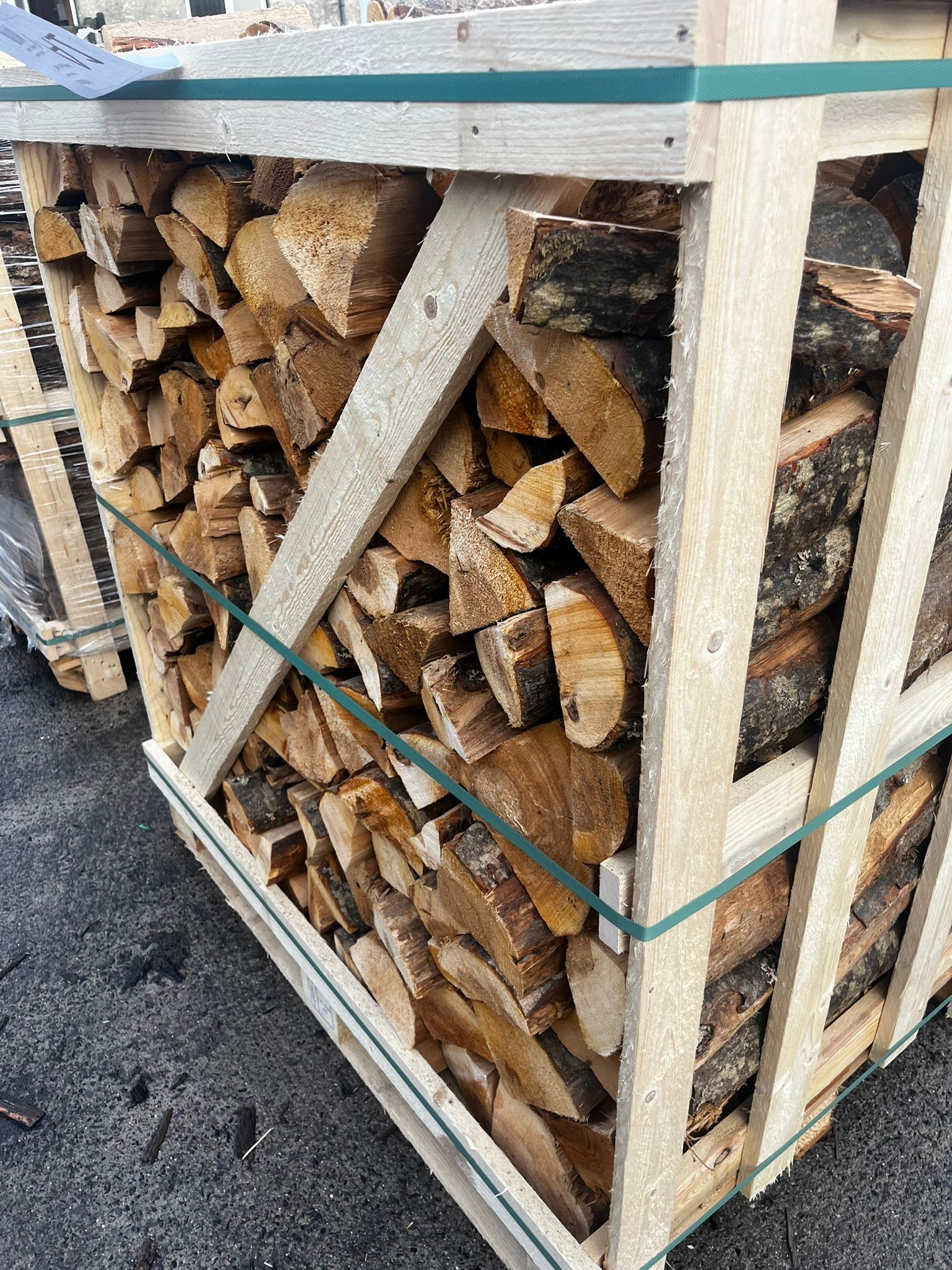 Stack of Alder firewood in a wooden crate on a concrete surface Murphys Direct UK