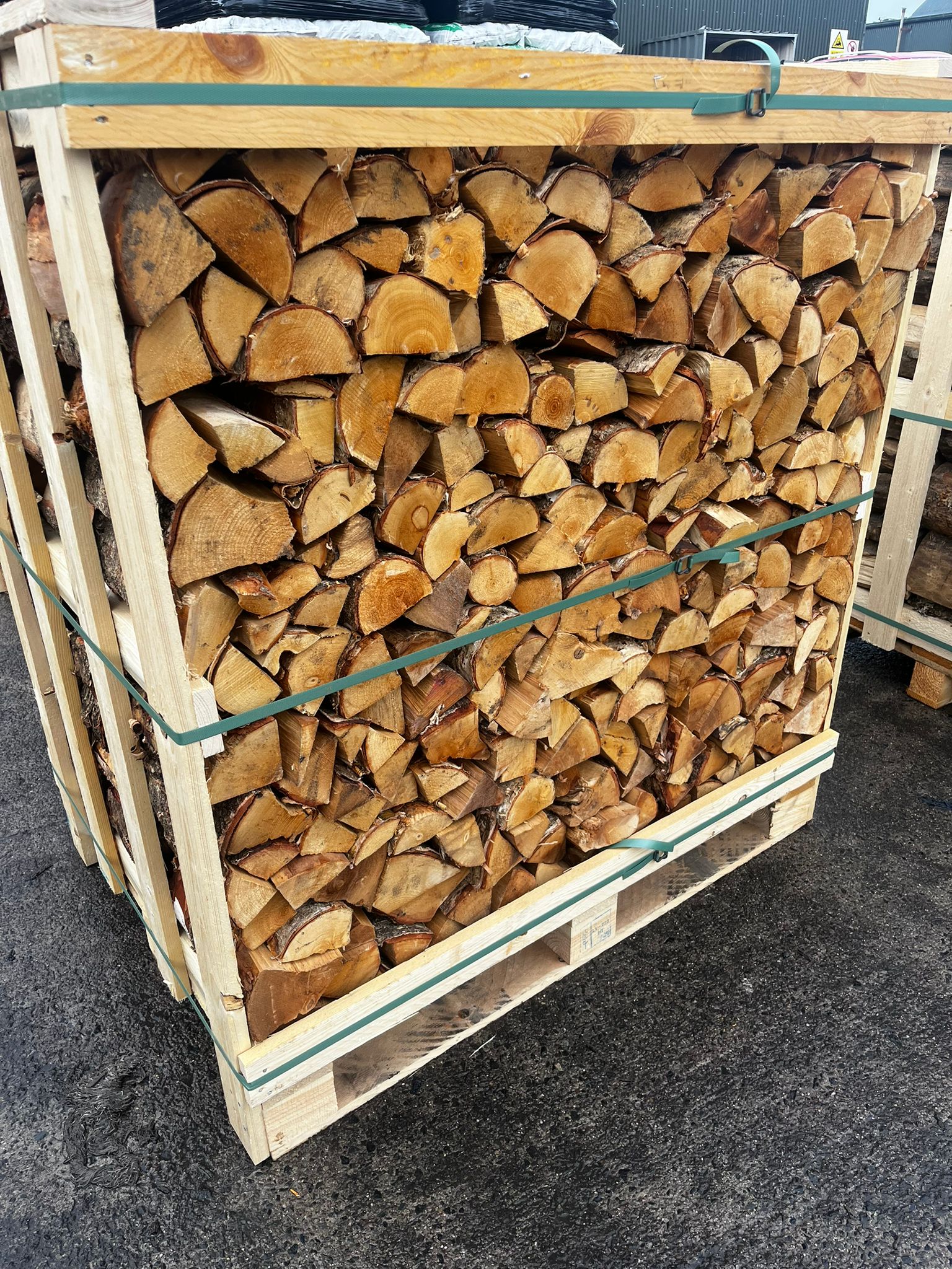 Stack of firewood in a wooden crate on a concrete surface Murphys Direct UK