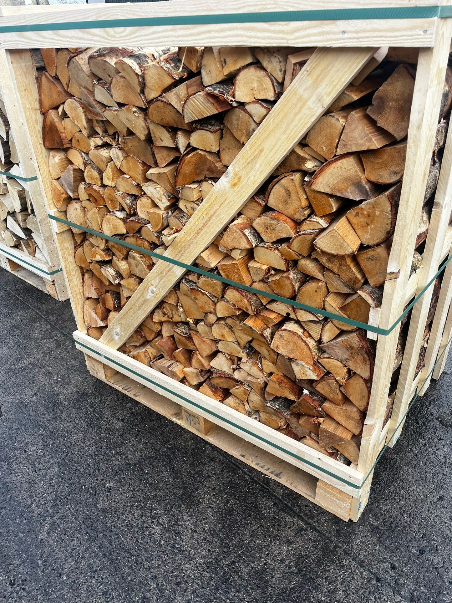 Stack of firewood in a wooden crate on a concrete surface Murphys Direct UK